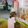 بالصور : في مشهد بريء و عفوي .. طفل يؤدي التحية لصورة خادم الحرمين الشريفين و يقبل يده